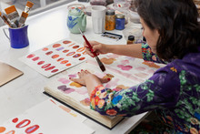 Side View Of Female Artist Using Paintbrush To Make Illustration