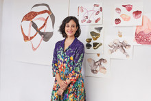 Smiling Artist Against Illustrations On Wall In Studio