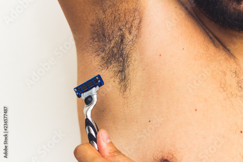 Fotografía man shaving armpits . holding razor in hands