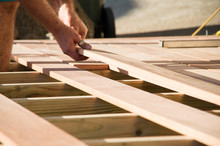 Man Placing A Plank Of Wood In A Deck Home Renovation