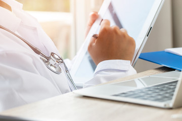 Healthcare medical hospital concept : Doctor intern using tablet computer with gown suite wearing Stethoscope on neck for seaching information treating patients in clinic