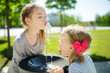 © MNStudio - Two sisters having fun with drinking water fountain on warm and sunny summer day.