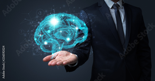 Cuadros en Lienzo Businessman holding human brain on his hand with logistics symbols around