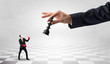 © ra2 studio - Small businessman fighting against big chessman on a big hand with chess board concept