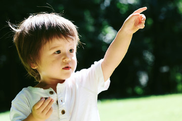 Toddler boy pointing to something outside in the summer