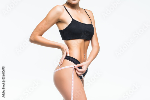 Fotografía Beautiful sporty young woman with measure tape around body measuring hips isolat