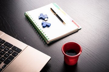 still life of a workplace , still life with block note, laptop, pen and a red cup of coffee over a black office desk. symbol of job