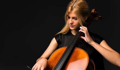 Wall Mural - Young girl playing the cello on isolated black background