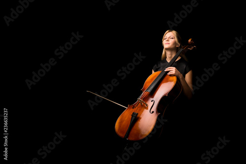 Fotomural Young girl playing the cello on isolated black background