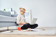 © baranq - Young woman sitting on floor at home working with laptop and documents