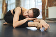 © pressmaster - Young female dancer lying on her stretched leg during relax exercise on the floor