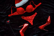 BDSM New Year flat lay. Sexy red woman accessories. Red shoes and spanking whip on the dark background. Sexy Santa for naughty boy.