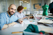© pressmaster - Happy young designer sitting by desk and sketching new fashion models in working environment