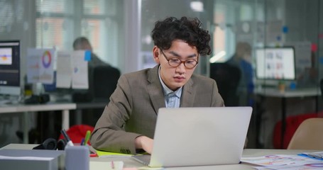 Young asian web designer putting on glasses
