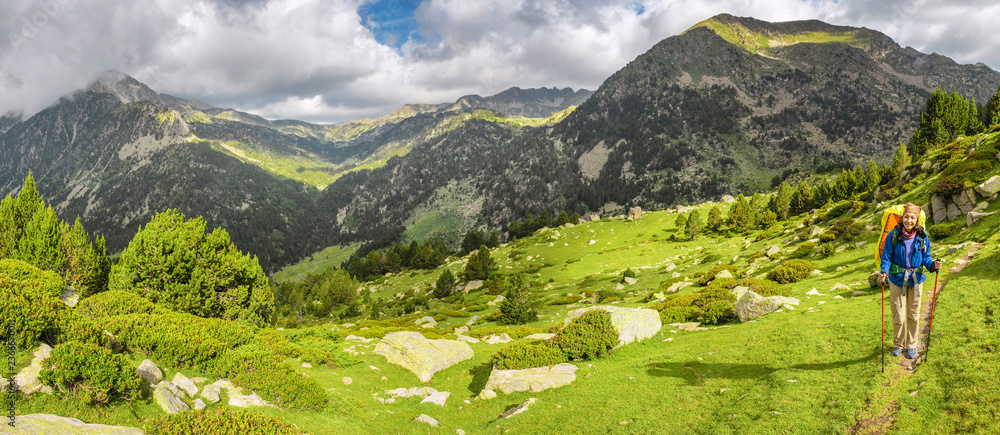 Obraz na płótnie Happy woman hiker travels in Pyrenees Mountains in Andorra and Spain. Nordic walking, recreation and trekking along GR11 path trail w salonie