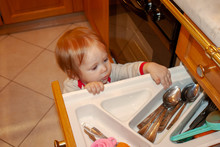 Baby Is Actively Exploring The Contents Of Kitchen Box. Safety Of The Little Explorer From Unwanted Objects And Sharp Corners, Doors And Drawers, To Which, Like A Magnet, Attracts The Young Know-all.