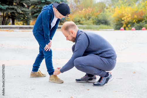 Fotografía Father tying shoelace of son while playing in a park