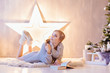 © Smile - Beautiful young woman laying and reading book under Christmas tree in a holiday interior