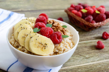 Wall Mural - Delicious and healthy oatmeal with banana, raspberries, nuts. Healthy breakfast. Fitness food. Proper nutrition.