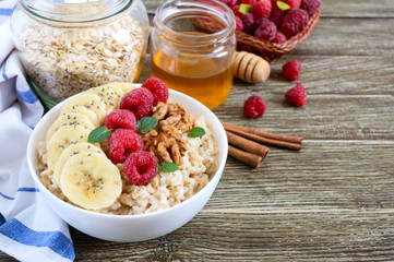 Wall Mural - Delicious and healthy oatmeal with banana, raspberries, nuts. Healthy breakfast. Fitness food. Proper nutrition.