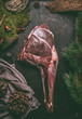 Raw aged leg of venison with bone on dark kitchen table background , top view. Raw meat leg of deer. Cooking preparation of venison roast