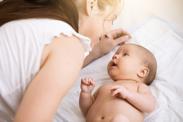 Young mother holding a newborn baby. Mom talks and laughs with her newborn son at home bedroom. Lifestyle happy multiracial family concept