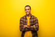 © luismolinero - Young african american man on vibrant yellow background keeping the arms crossed in frontal position