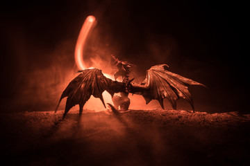 Silhouette of fire breathing dragon with big wings on a dark orange background