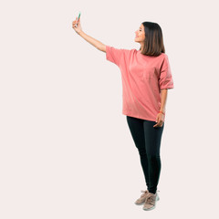 Full body of Young girl with pink shirt taking a selfie with the mobile