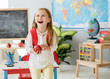 © tan4ikk - Little laughing blond girl holding an apple in the school classroom