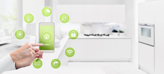 smart home automation control concept hand touch cell phone screen with green symbols icons on kitchen background web banner and copy space template