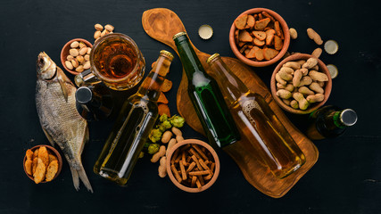 Wall Mural - A selection of beer and snacks. Light beer, dark beer, live beer. On a black wooden background. Free space for text. Top view.