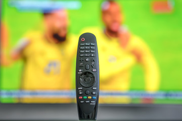 black remote for tv on the table, two football players in yellow uniform, football match