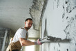 © Kadmy - Plasterer using screeder spraying putty plaster mortar on wall