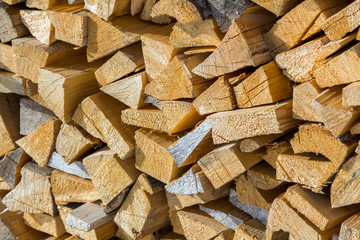 Poster - Neatly piled stack of chopped dry trunks wood outdoors on bright cold winter sunny day, abstract background, Fire wood logs prepared for winter, ready for burning. Environment protection concept.