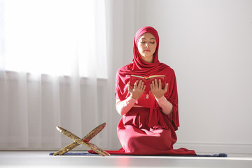 Wall Mural - Muslim woman in hijab reading Koran indoors