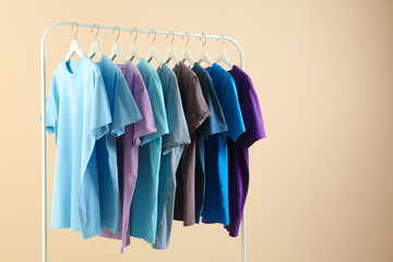 Men's clothes hanging on wardrobe rack against light background