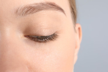 Sticker - Young woman with beautiful natural eyelashes on gray background, closeup