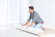 © New Africa - Man rolling out new carpet flooring indoors. Space for text