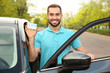 © New Africa - Young man holding driving license near open car