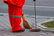 Municipal worker sweeping the road with broomstick and collects garbage in scoop. Sanitation worker sweep street. Street sweeper cleaning footpath in the city. Cleaning, maid service