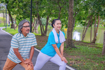 They are happy Asian couple.They  are warm up for exercise in park.They smile and be happy in good time,this photo relates about a husband,wife,love Photo concept Health and relax time.