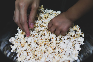 Two hands grabbing for fresh popcorn.A  women and kid grabbing fresh popcorn.