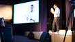 © Right 3 - Presenter Presenting Presentation to Conference Audience. De-focused Blurred . Lecturer on Stage at Tech Forum. Speaker Giving Speech in Conference Hall Auditorium. Copy Space Screen Background.