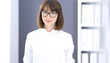 © rogerphoto - Young brunette business woman looks like a student girl working in office. Caucasian  girl standing straight
