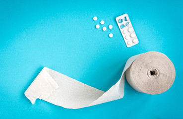 Wall Mural - Toilet paper and tablets on blue background. Pills from poisoning.