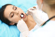 © rogerphoto - Young female patient visiting dentist office.Beautiful woman with healthy straight white teeth sitting at dental chair with open mouth during oral checkup while doctor working at teeth