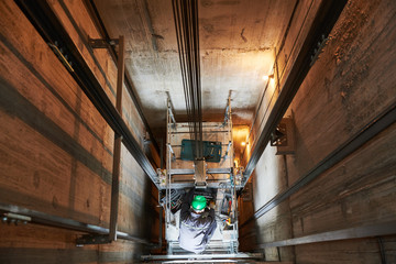 Wall Mural - lift machinist repairing elevator in lift shaft