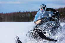 In Deep Snowdrift Snowmobile Rider Driving Fast. Riding With Fun In White Snow Powder During Backcountry Tour. Extreme Sport Adventure, Outdoor Activity During Winter Holiday On Ski Mountain Resort.