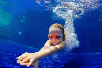 Wall Mural - Happy family in swimming pool. Smiling child in goggles swim, dive in pool with fun - jump deep down underwater. Healthy lifestyle, people water sport activity, swimming lessons on holidays with kids